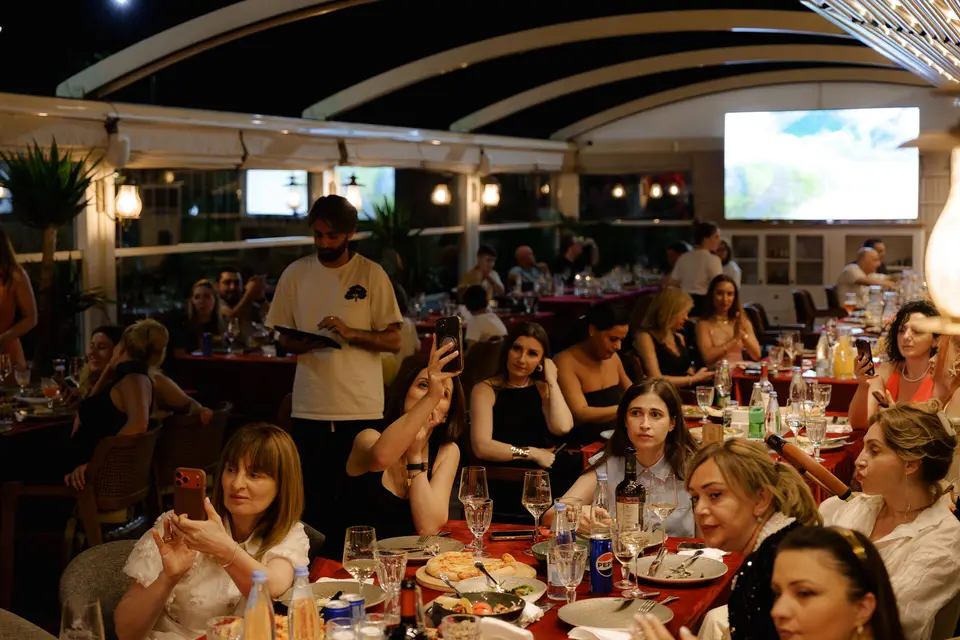 Guests at tables watching a football match on screen