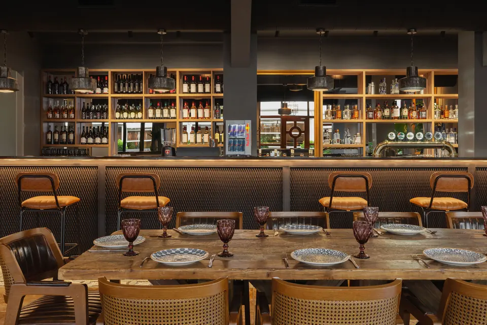 Laid dining table and stools in front of the pub bar