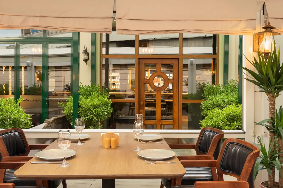 A table laid for four beside the pergola windows and greenery
