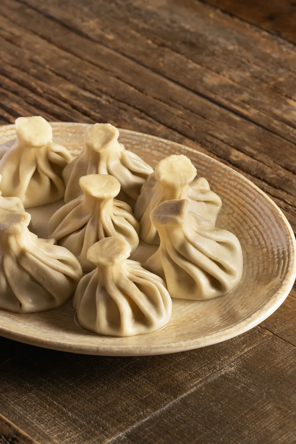 Six khinkali on a ceramic plate on a wooden table